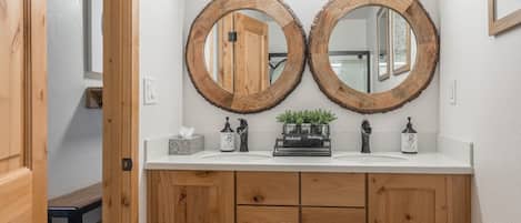 Un baño con dos espejos de madera, una encimera blanca y un mueble de tocador de madera con cajones.