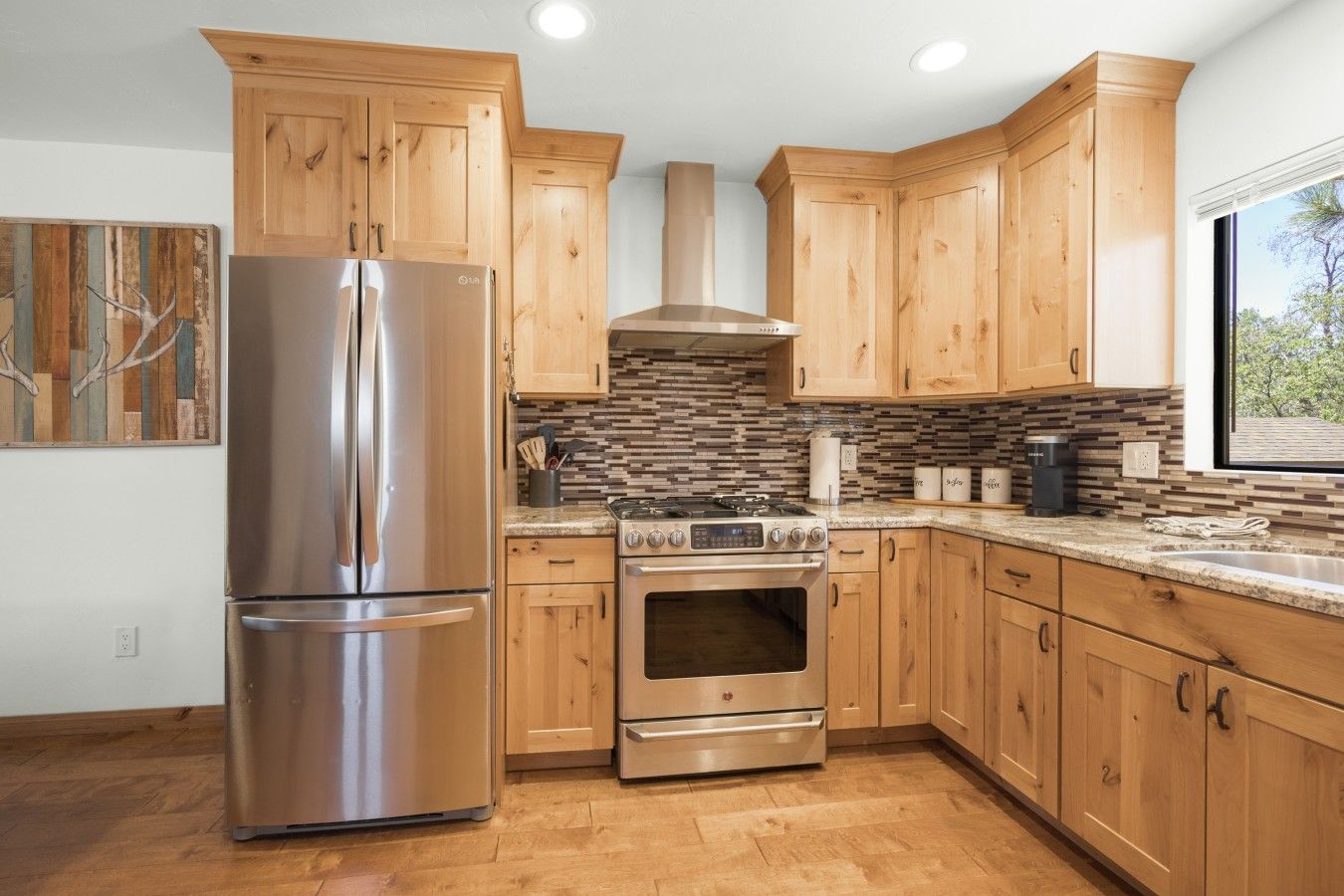 A modern kitchen with wooden cabinets, stainless steel appliances, and a tiled backsplash.