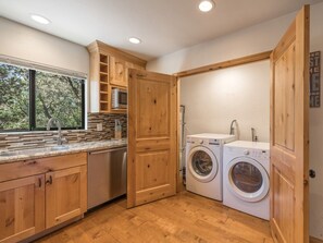 A compact kitchen with wooden cabinets, a built-in microwave, and a large window.