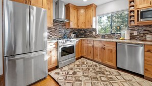 Una cocina moderna con armarios de madera, electrodomésticos de acero inoxidable y un tapete estampado.