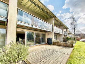 A two-story building with large glass windows, a wooden deck, and a garden area. - 4 bedroom accommodation in South Cerney (South Cerney)