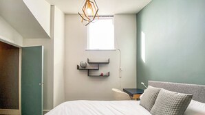 Une chambre moderne avec un grand lit, un bureau et un globe terrestre posé sur une étagère.