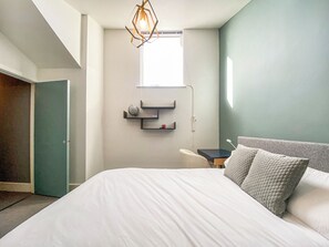A modern bedroom with a large bed, a desk, and a globe on a shelf. - 4 bedroom accommodation in South Cerney (South Cerney)