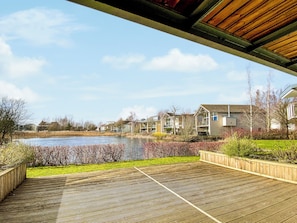 A wooden deck with a view of a pond and houses in the background.