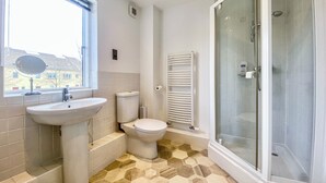 Une salle de bain équipée d’un lavabo, de toilettes et d’une douche à parois de verre.