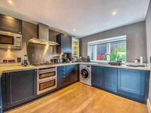 A modern kitchen with built-in appliances, a large window, and a washing machine.