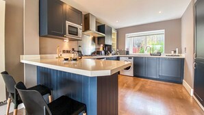 A modern kitchen with dark cabinetry, a central island, and a built-in washing machine.