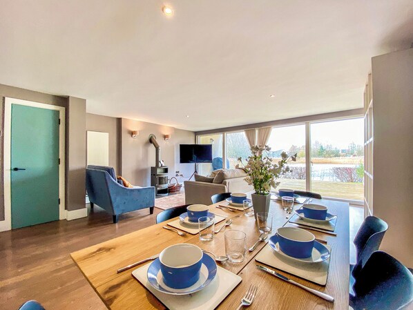 A modern living room with a dining area, a TV, and a large window with a view.