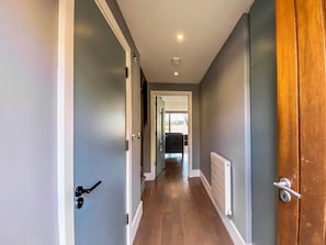 A hallway with a wooden floor, grey walls, and a door on the right.