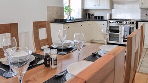 A modern kitchen with white cabinets, a stainless steel range hood, and a built-in oven. - The Byre @ Camp Douglas (Castle Douglas)