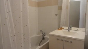 Un baño con bañera, lavamanos, espejo y cortina de ducha.