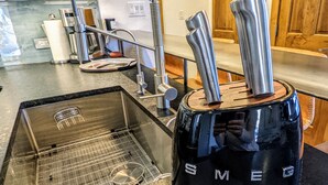 Eine Küche mit einem schwarzen Wasserkocher, einer Edelstahlspüle und einem modernen Wasserhahn.
