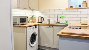 Una cocina compacta con lavadora, microondas, pileta y encimeras de madera.