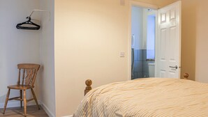 Un dormitorio con una cama, una silla y una puerta que da al baño.