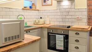 Cocina compacta con salpicadero de azulejos blancos, horno empotrado, tostadora y ventana con vistas.