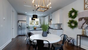 A modern kitchen with white cabinets, a round dining table, and black chairs.