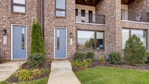 A two-story brick building with a front entrance, a small balcony, and a well-maintained lawn.