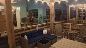 Eine Holzterrasse mit einer Couch, Stühlen und einem Tisch.