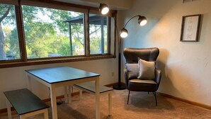 A room with a window, a desk, a chair, and a floor lamp.