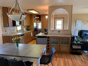 Una cocina moderna con armarios de madera, una isla central y una zona de comedor con mesa y sillas.