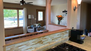 A kitchen with a stone countertop, a gas stove, a coffee maker, and a view of the outside through a window.