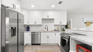 Una cocina moderna con armarios blancos, electrodomésticos de acero inoxidable y encimera de granito.