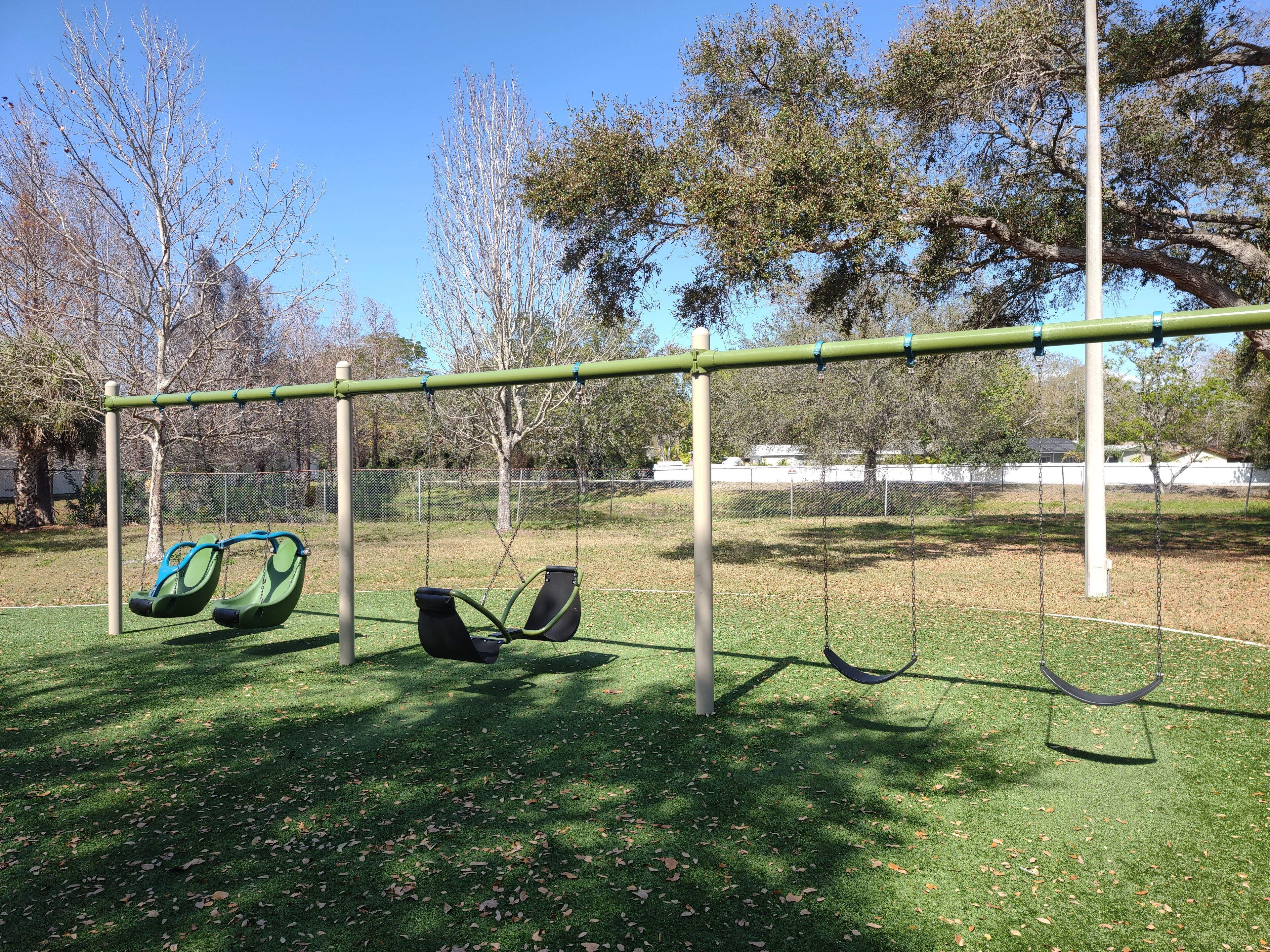 A playground with swings and a green artificial turf surface.