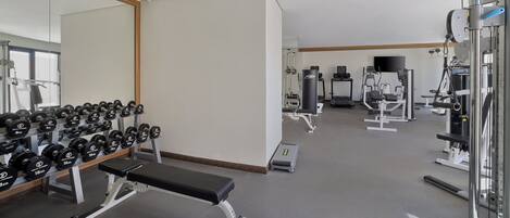 A gym with various exercise equipment, including dumbbells, a bench, and weight machines.