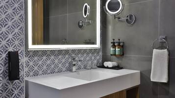 Un baño moderno con un espejo grande, dos lavamanos y un perchero para toallas.