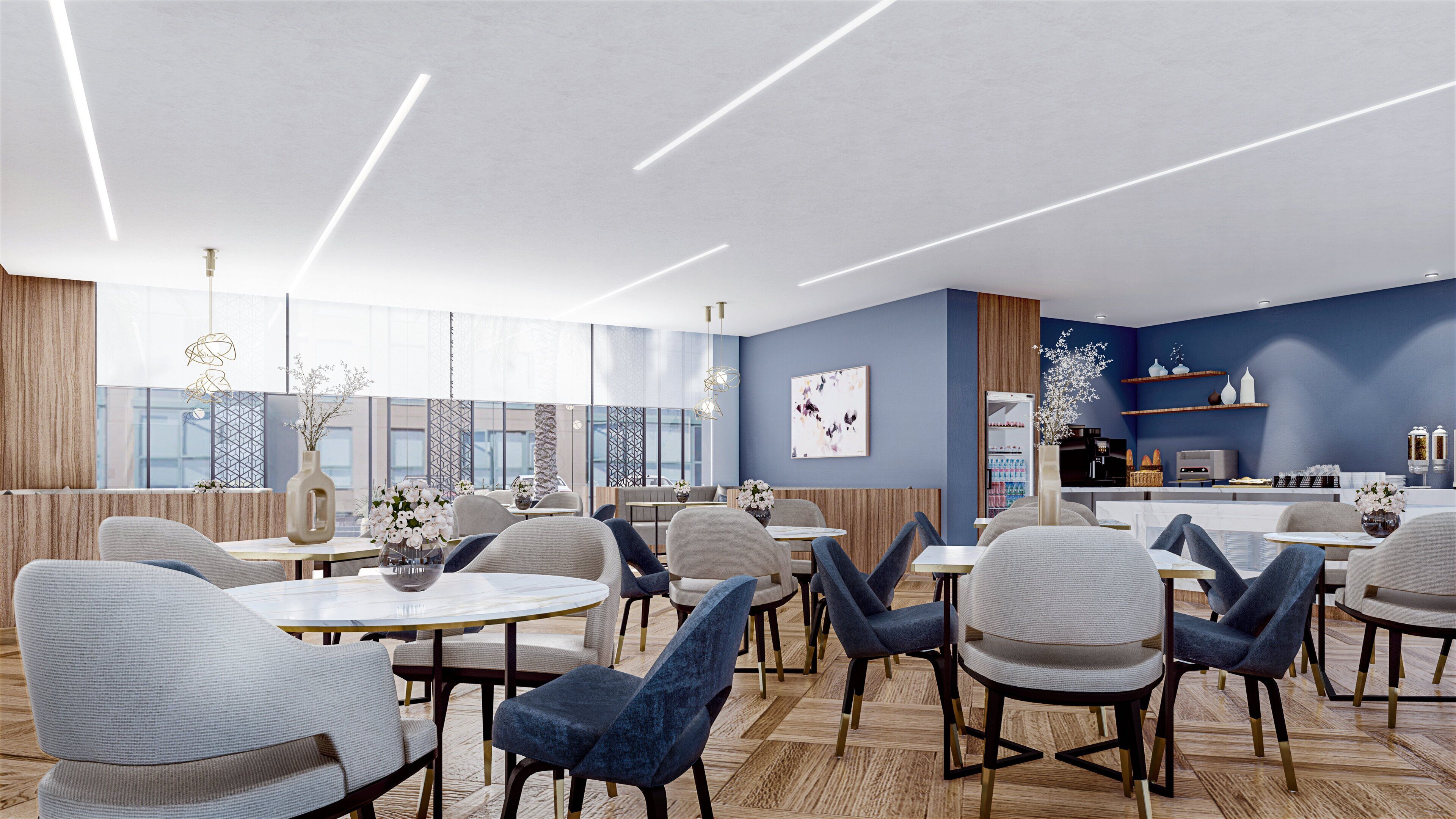 A modern dining area with round tables and chairs, a kitchen in the background, and large windows providing natural light.