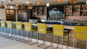Un espace bar doté d’un long comptoir, de plusieurs étagères remplies de bouteilles d’alcool et d’un écran de télévision.