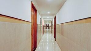 Um corredor longo e bem iluminado, com portas de madeira e paredes bege.