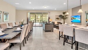 A spacious dining area with a long table, multiple chairs, and a television on the wall. - Dazzling 9BR Villa with Pool& Spa, Close to Disney (Four Corners)
