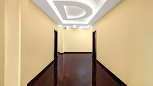 Un pasillo moderno de hotel con piso pulido, paredes color crema y techo con un gran logo iluminado con la letra 'D'.