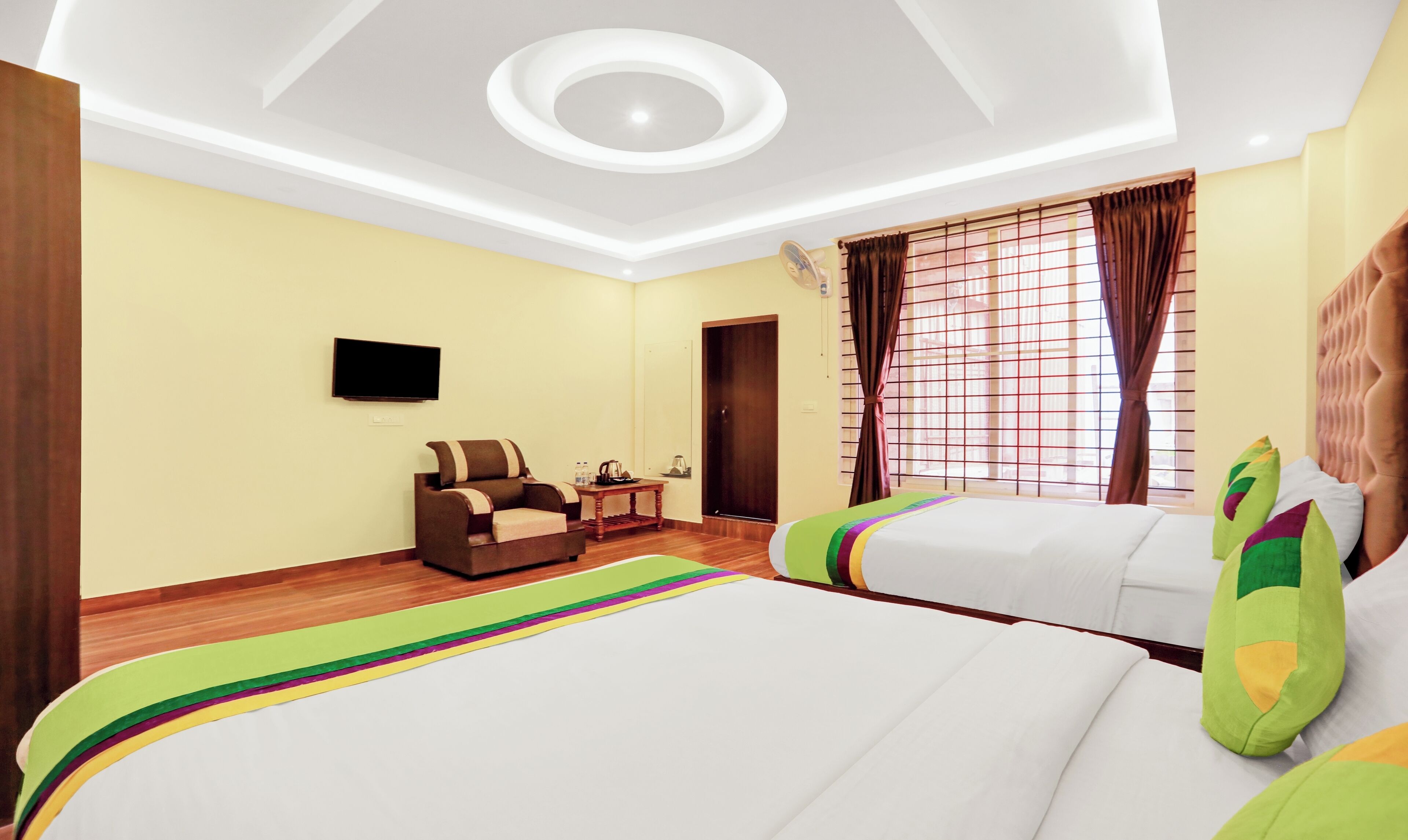 Habitación de hotel con cama, sofá, televisor y ventana con cortinas.