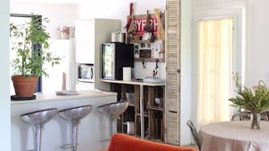 A modern kitchen with a central island, bar stools, and a red sofa.