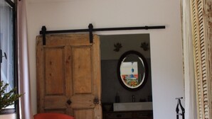 A bedroom with a bed, a wooden wardrobe, a chair, a table, and a mirror.