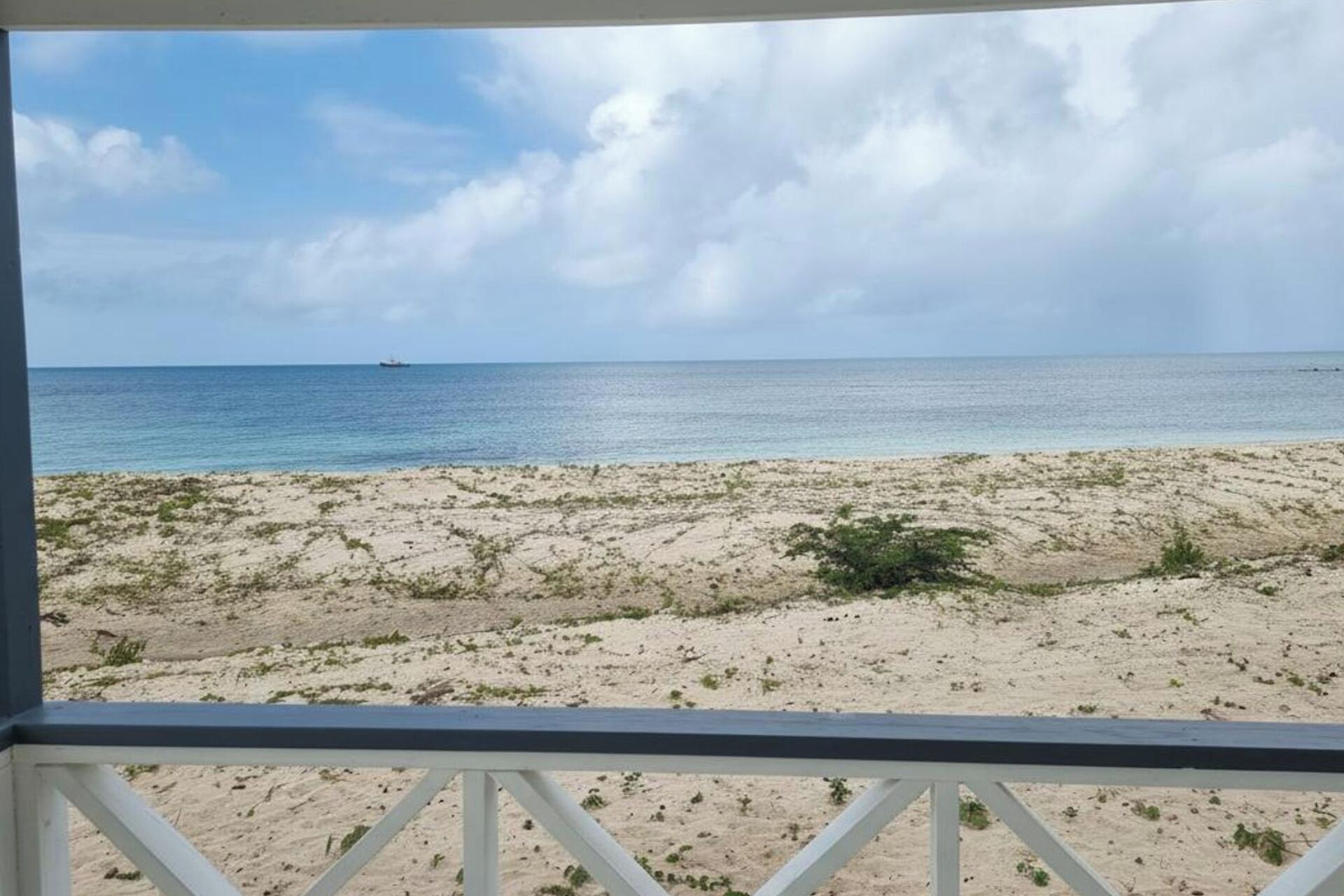 Une vue sur la plage depuis un balcon doté d’une balustrade, avec une plage de sable et l’océan en toile de fond.