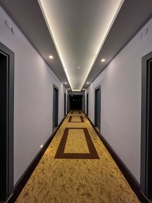 A long, narrow hotel corridor with a patterned carpet, recessed lighting, and doors on both sides. - Ankara Santral Otel (Ankara)