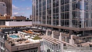 A modern hotel with a rooftop pool area, outdoor seating, and a view of the cityscape.
