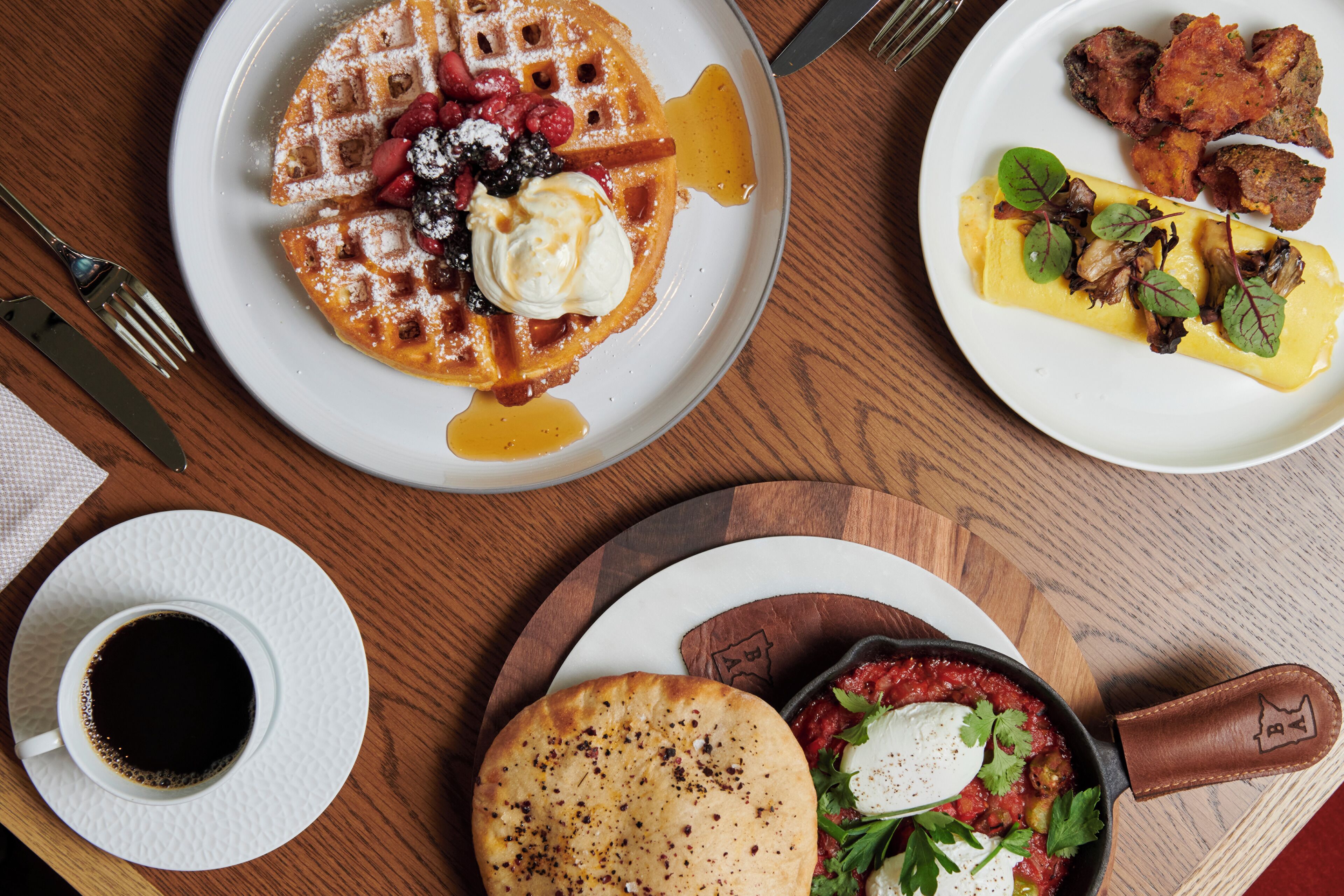 A breakfast setting with waffles, eggs, and a coffee cup on a wooden table.
