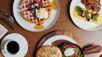A breakfast setting with waffles, eggs, and a coffee cup on a wooden table.