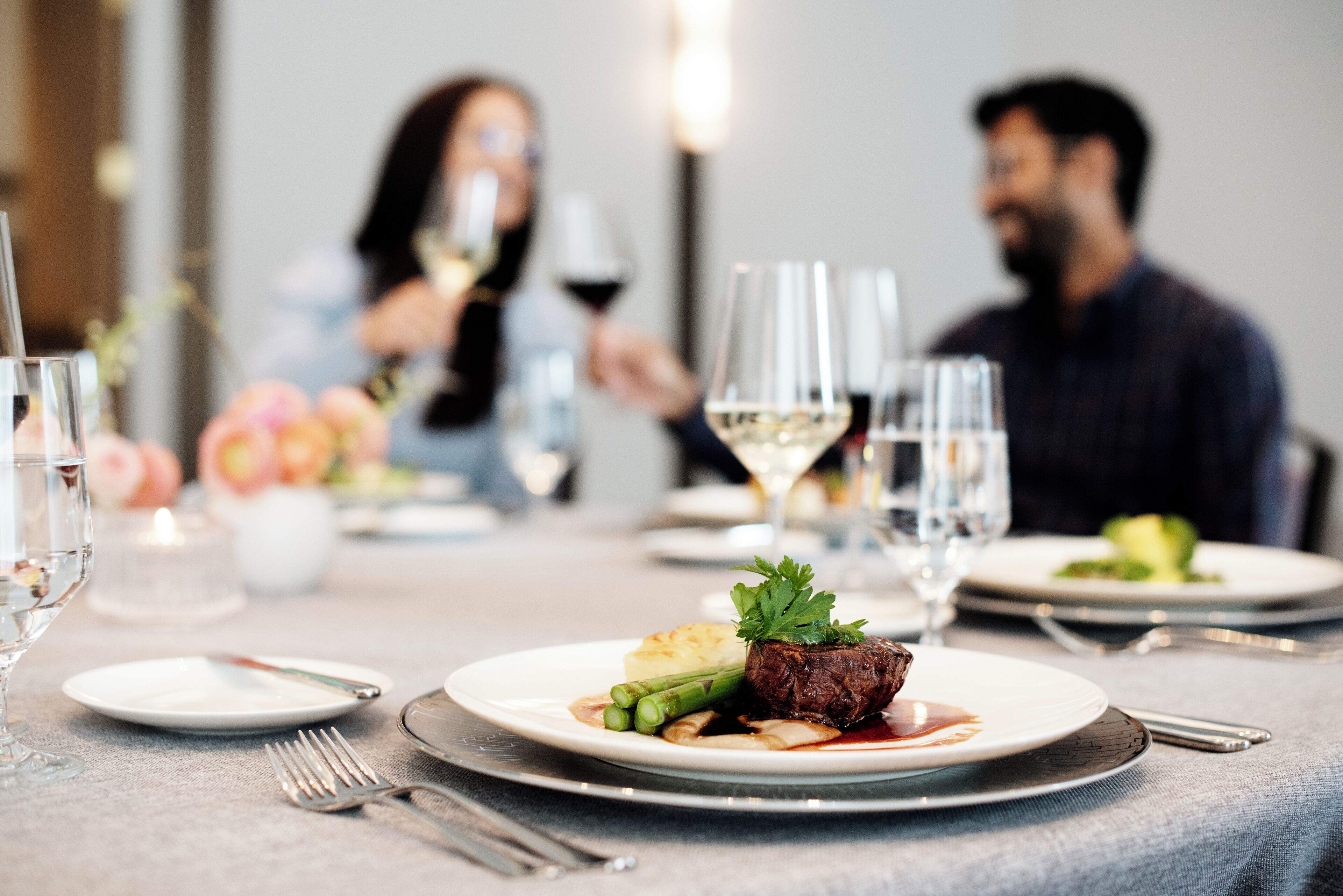 A dining table set with plates of food, glasses, and cutlery.