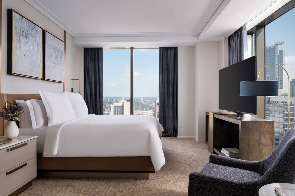 Een moderne hotelkamer met een groot bed, een televisie en uitzicht over de stad.