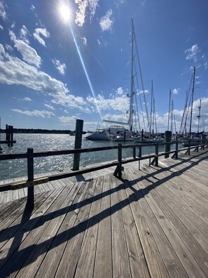 Eine hölzerne Pier mit an einem Hafen befestigten Booten unter blauem Himmel.