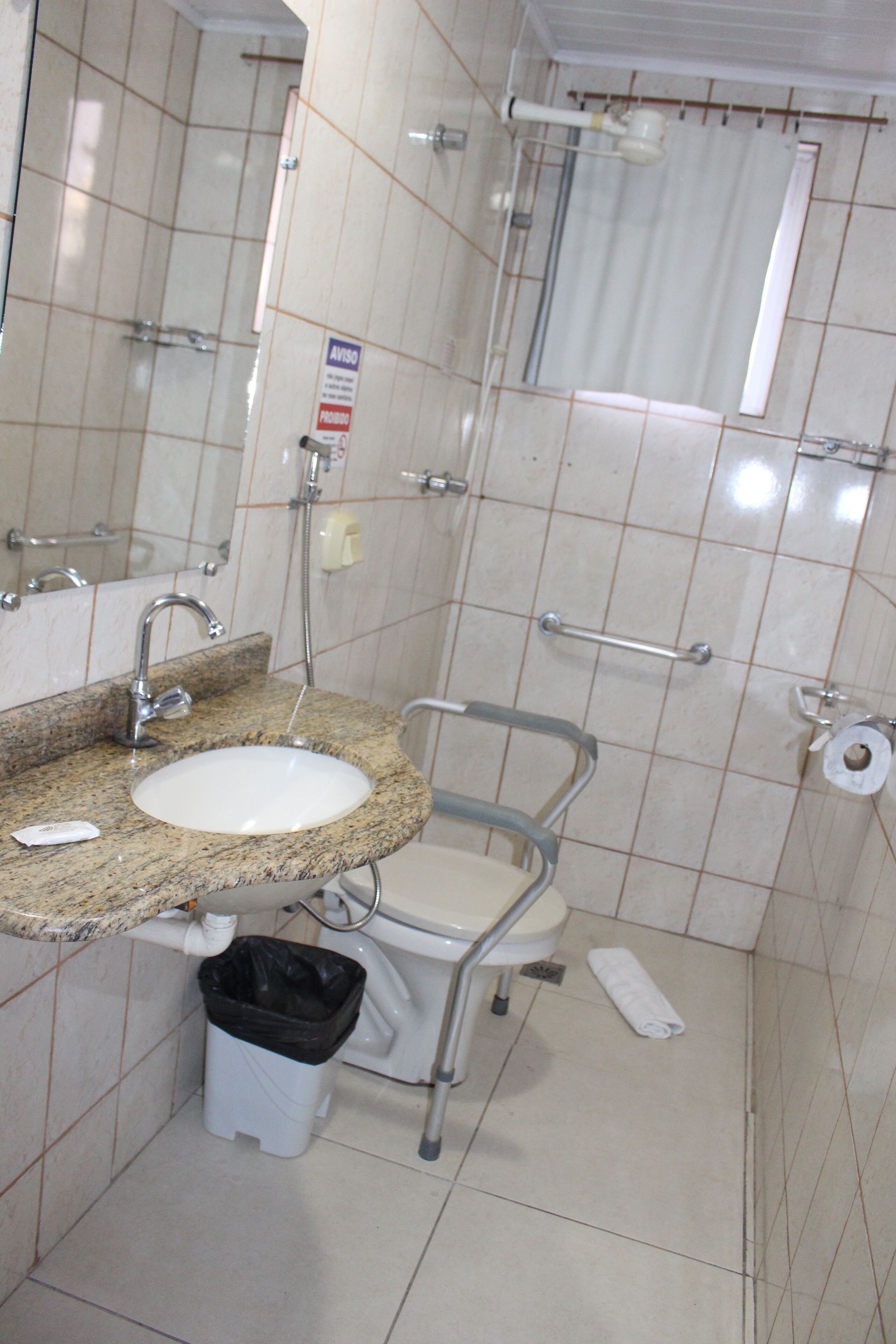 A bathroom with a sink, mirror, toilet, and grab bar.