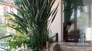 A stone planter with large green plants, a curved stone wall, and a wooden ceiling.
