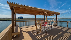 Una terraza de madera con pérgola, una mesa y sillas.