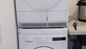 A compact, white stacked washer and dryer unit in a small laundry room. - 4-6 PERSON APARTMENT (Albitreccia)
