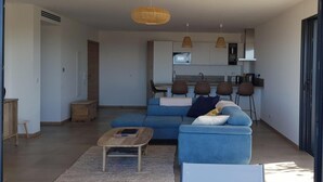 A modern living room with a blue sofa, a coffee table, and a kitchen in the background. - 4-6 PERSON APARTMENT (Albitreccia)
